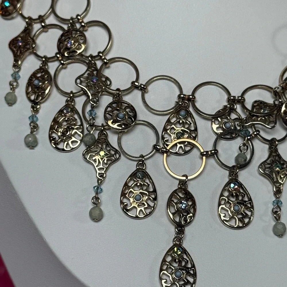 Silver tones necklace with intricate filigree and green and blue dangling charms